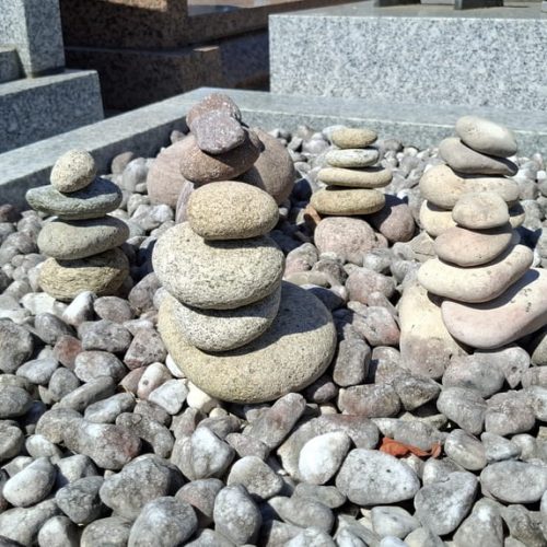 Cinq piles de galets, posés sur une pierre tombale, au cimetière de Saint-Denis-en-Val