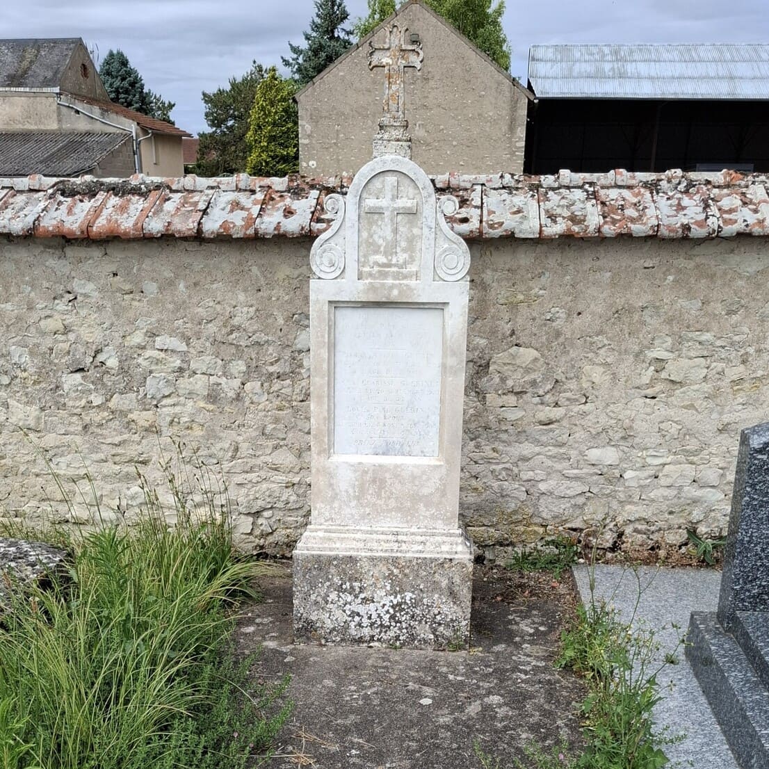 photographie d'une tombe ancienne dans un cimetière près d'Orléans, avant le nettoyage. La tombe est sale, noircie, la croix en pierre est couverte de lichen et de mousse. La semelle en béton est couverte d'herbe.