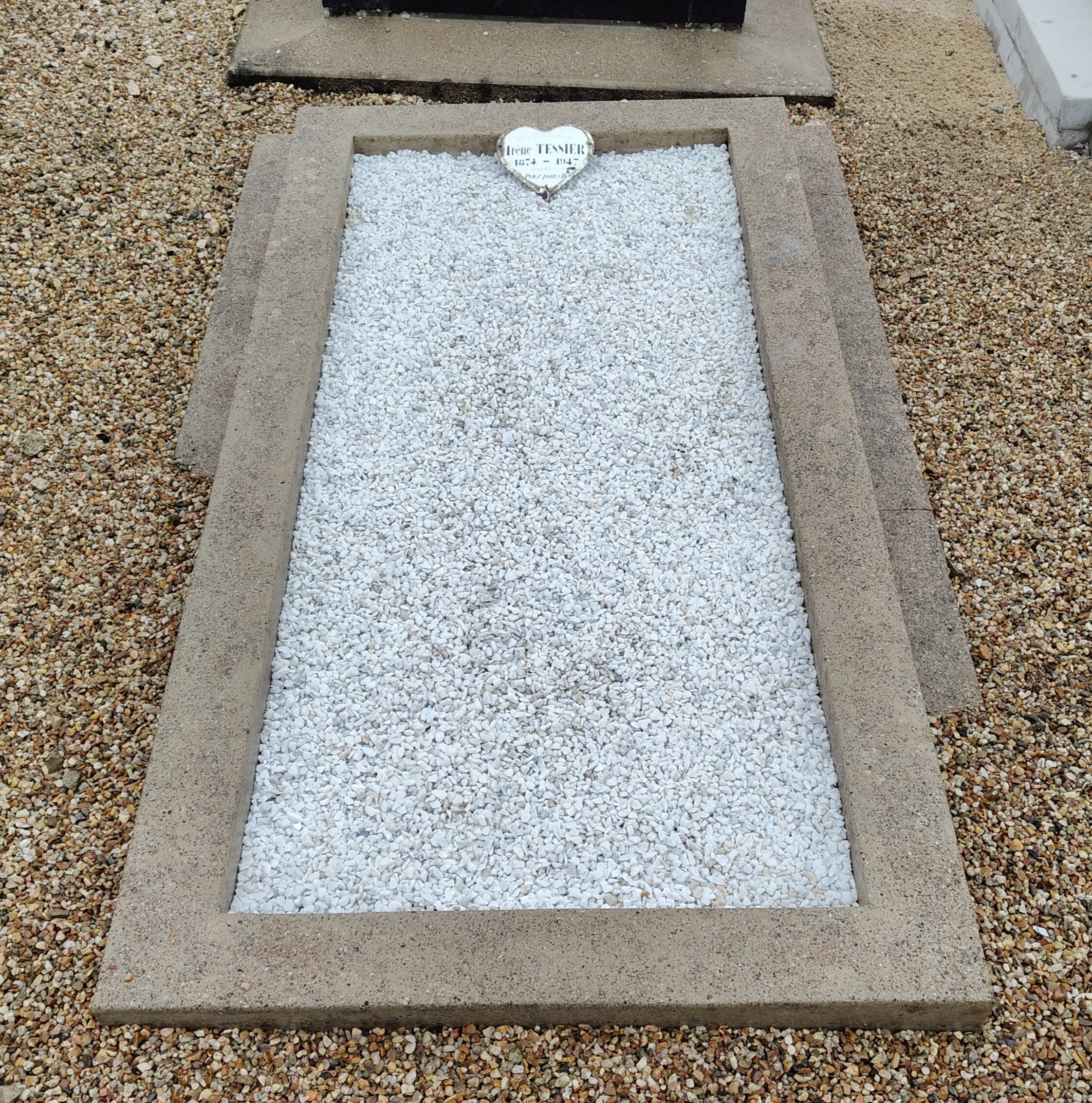 Tombe d'Irène TESSIER, située dans le cimetière communal de Yèvre-le-Chatel (45). La photo est prise après le nettoyage, elle est toute propre, les tâches ont disparu, et les cailloux ont été remplacés par des éclats de marbre.